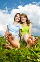 6264437-Two-young-teenage-girl-friends-sitting-barefoot-on-summer-meadow-Stock-Photo.jpg