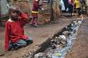 A_young_boy_sits_over_an_open_sewer_in_the_Kibera_slum,_Nairobi.jpg