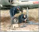 1Squadron RCAF ground crew tend to Hawker Hurricane, Leading Aircraftman PJ Thurgeon removes port wheel cause of faulty brakes, Sergeant Bob Fair checks to see if craft should go into maintenance to be repaired.jpg
