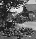 6 Fallschirmjäger Division march toward disarmament area in Soest, Holland Still well equipped, several of the men carry a Panzerfaust, note the growing pile of German equipment lining the road.jpg