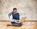 16859823-happy-indian-businessman-with-leg-behind-his-head-typing-on-his-laptop-and-smiling-in-the-office-at-.jpg