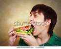stock-photo-the-hungry-young-man-aggressively-eats-a-hamburger-fast-food-133598540.jpg