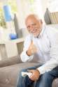 7899224-Older-man-sitting-on-couch-giving-thumb-up-while-playing-computer-game-looking-at-camera-smiling--Stock-Photo.jpg