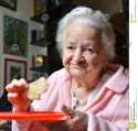 old-woman-eating-slice-bread-home-47960809.jpg