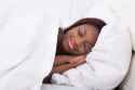 27393833-Smiling-African-American-woman-sleeping-in-bed-Stock-Photo[1].jpg