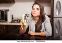 stock-photo-cute-young-hispanic-woman-chewing-a-banana-while-sitting-in-the-kitchen-232801840.jpg